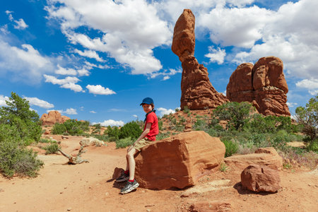 Boy Resting near Balanced Rock in Arches National Park in Utah. Landscape Photo in the Summerの写真素材