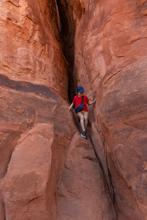 Young Hiker Boy Climbing Rock in Arches National Park, Utah, United States.の写真素材