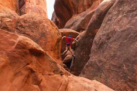 Young Hiker Boy Climbing through the Narrow Path in Fiery Furnace in Arches National Park, Utah, United States.の写真素材