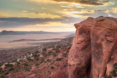 A stunning sunset view from Devils Garden Trail in Arches National Park, Utah. The rugged red rock formations and expansive desert landscape are illuminated by the warm glow of the setting sun.の写真素材
