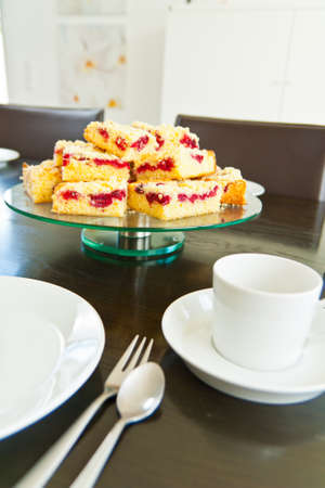 Raspberry Streusel Cake sliced on a table with dishes and coffee cupsの写真素材