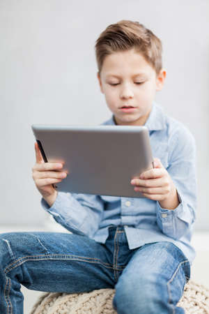 Boy sitting  in the living room using a tablet pc