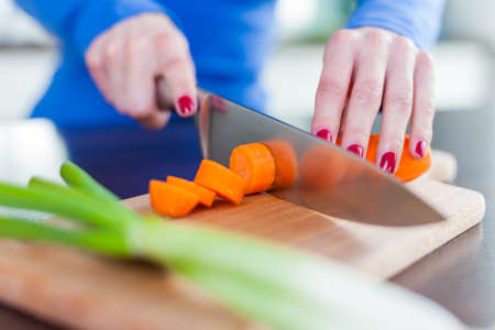 A young female chopping fresh vegetables in the kitchenの写真素材