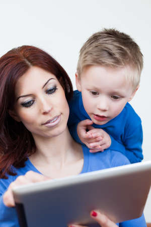 A Mother and her Son sitting on a couch using a Tablet PCの写真素材