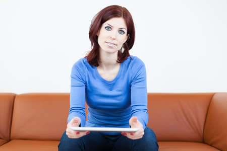 Attractive Woman sitting on a couch with Tablet PC