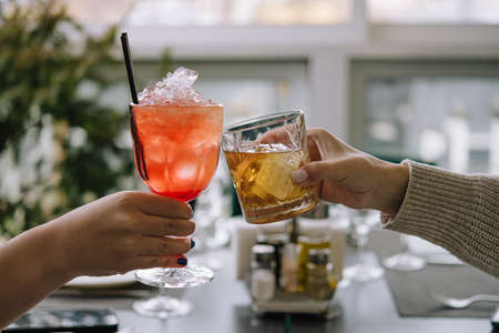 Friends toasting with glasses of whiskey and strawberry cocktail