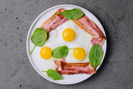 Fried eggs and bacon for breakfast on a plateの写真素材