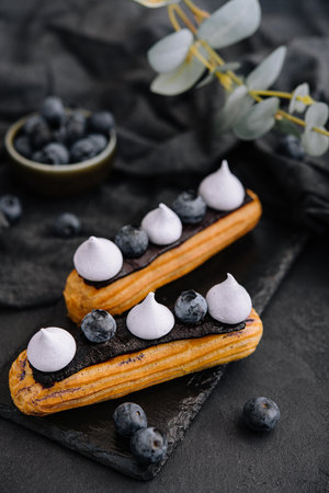 Beautiful and tasty eclairs on a slate board with petals