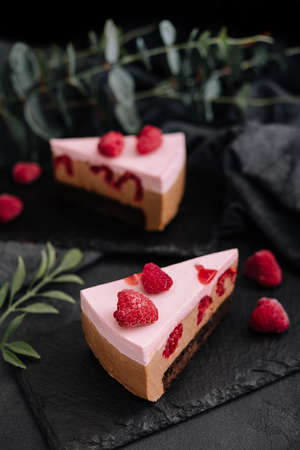 Pieces of cheesecake with raspberries on black boardの写真素材
