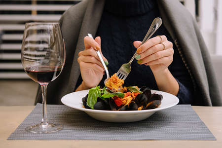 beautiful woman eating pasta with mussels in a restaurantの写真素材