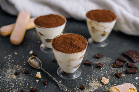 Italian dessert tiramisu in glass and eclairs with chocolate slicesの写真素材
