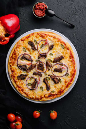 italian pizza with tomatoes, cheese, onions on blackの写真素材