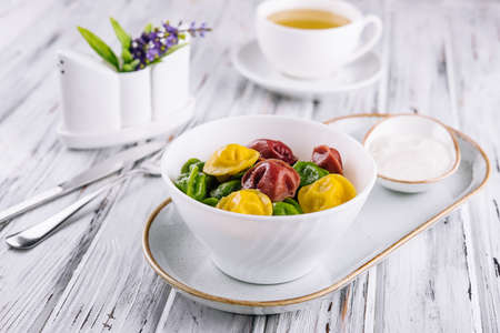 Cooked multi-colored tortellini dumplings close-up in a bowlの写真素材