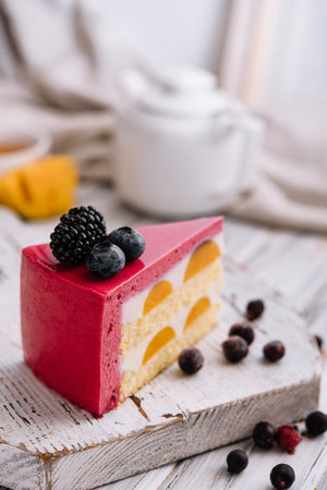 A slice of a pink strawberry cheesecake served with fresh berries on a white boardの写真素材