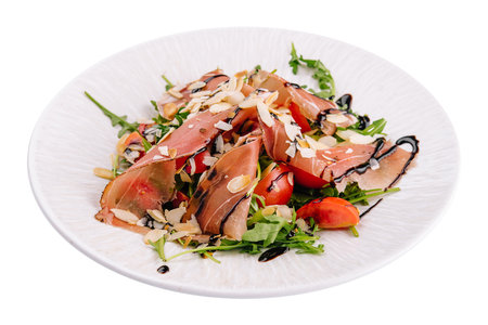 Salad with prosciutto, tomato, arugula leaves on plateの写真素材