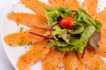 Slices of raw salmon fillet on white plateの写真素材