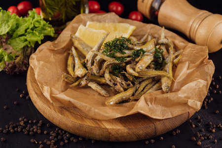 Hot fried smelt fish with salt and herbs on brown paperの写真素材