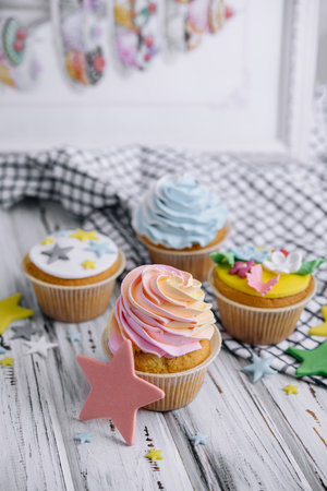 Multiple colorful nicely decorated muffins on a wooden backgroundの写真素材