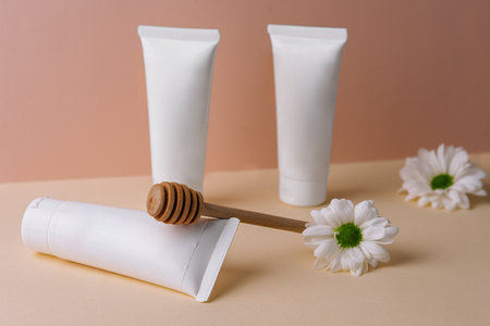 Honey infused cream with daisies. white bottles cosmetics.の写真素材