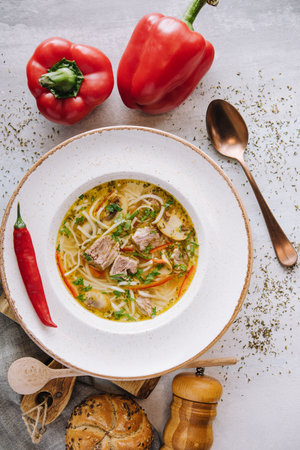 Chicken soup with noodles and vegetables in white bowl
