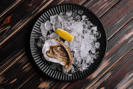 Fresh raw open oyster with ice and lemon slicesの写真素材
