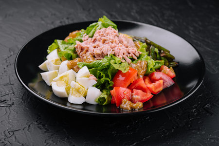 Tuna and vegetable salad on black plateの写真素材