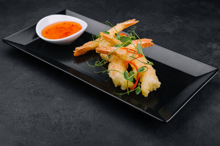 Fried shrimps tempura with sweet chili sauce on black stone plateの写真素材