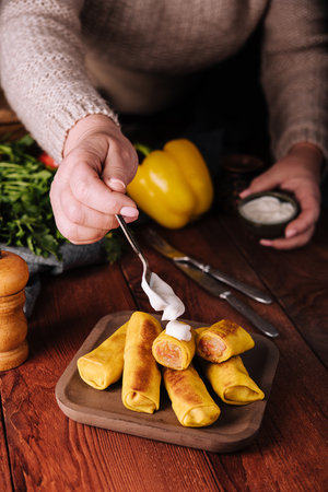 Woman adding sour cream to pancakesの写真素材