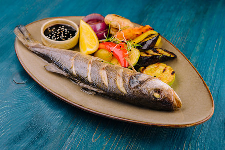 Seabass baked with grilled vegetables on plate