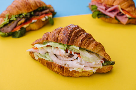 croissant sandwich ham on yellow with blue backgroundの写真素材