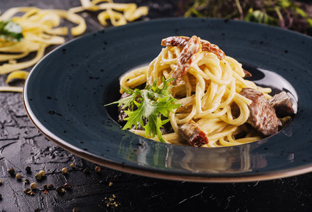spaghetti with veal pieces and arugula on plateの写真素材