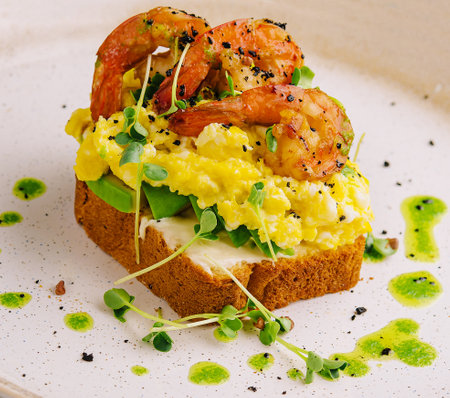 Scrambled eggs with avocado and shrimps on plateの写真素材