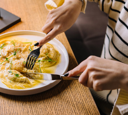 young woman eating tasty ravioli in cafeの写真素材