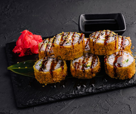 Warm sushi with ginger and wasabi served on a black stone plateの写真素材