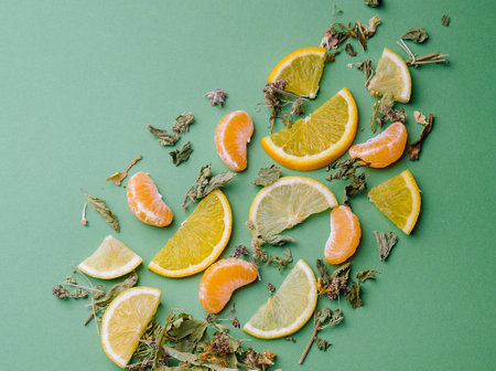 Leaf tea with orange and tangerine slices on green backgroundの写真素材