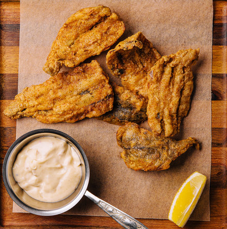 fried cod fillet pieces on wooden trayの写真素材