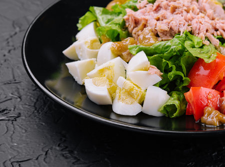 Tuna and vegetable salad on black plateの写真素材