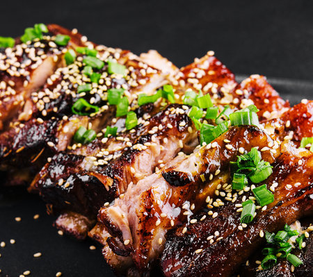 sliced BBQ pork ribs on black plateの写真素材