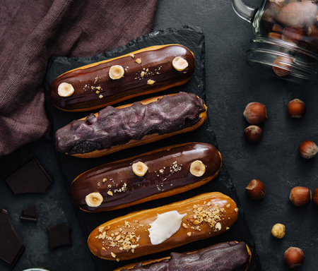 Sweet chocolate eclairs on black wooden board