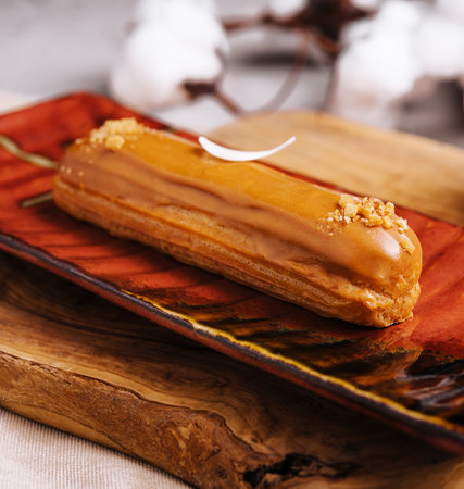 Appetizing eclair with caramel glaze and peanuts and coffeeの写真素材