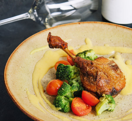 Confit duck leg with broccoli and tomatoesの写真素材