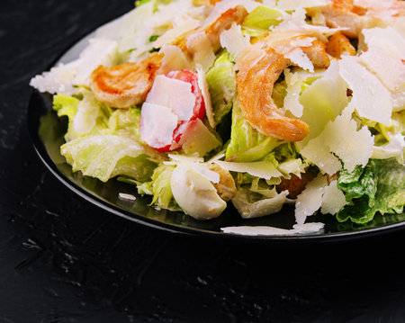 Delicious fresh caesar salad on black plateの写真素材