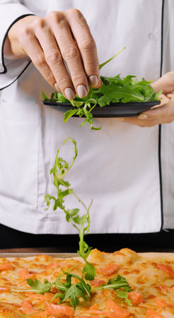 the chef decorates salmon pizza with arugulaの写真素材