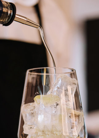 bartender pours alcohol into a glass
