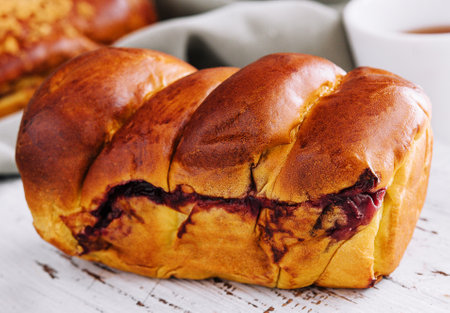 Delicious baked bun with cherry on white wood