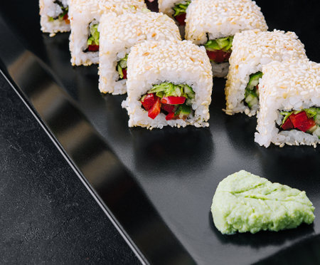 vegetarian sushi maki rolls with sesame seeds on black plateの写真素材