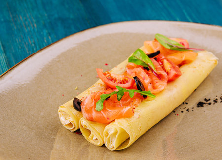 Delicious thin pancakes with salmon and sour cream on plateの写真素材