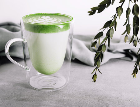 Glass of hot matcha green tea latte with tulip patternの写真素材