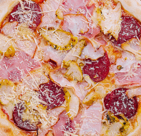 pizza with ham, pepperoni and chickenの写真素材