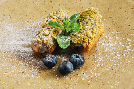 Tasty eclairs with pistachios and cheesecake on platesの写真素材